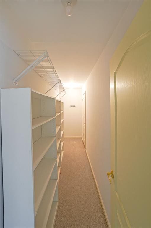 hall featuring baseboards and light colored carpet