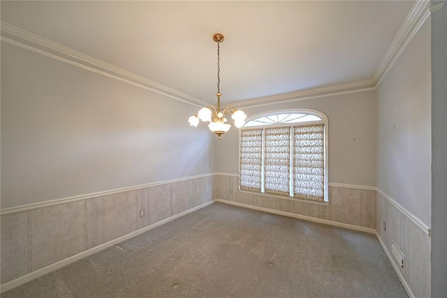 carpeted spare room featuring a wainscoted wall, ornamental molding, and a notable chandelier