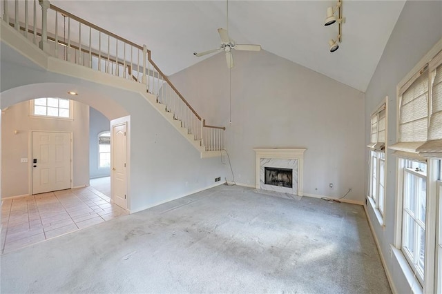 unfurnished living room with carpet floors, high vaulted ceiling, and a high end fireplace