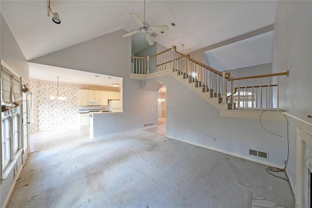 unfurnished living room with arched walkways, visible vents, light carpet, high vaulted ceiling, and wallpapered walls