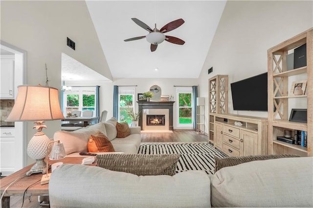3320 Goldmist Dr, Buford, GA 30519 - living room featuring high vaulted ceiling, wood finished floors, ceiling fan, and a lit fireplace