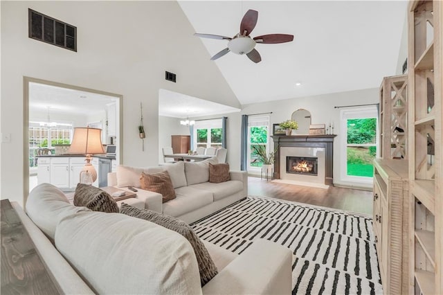 3320 Goldmist Dr, Buford, GA 30519 - living room featuring a chandelier, a glass covered fireplace, healthy amount of natural light, a ceiling fan, and high vaulted ceiling