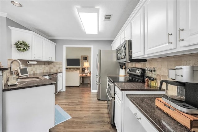 3320 Goldmist Dr, Buford, GA 30519 - kitchen featuring appliances with stainless steel finishes, a sink, white cabinets, ornamental molding, and wood finished floors