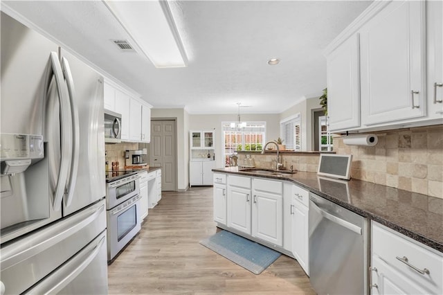 3320 Goldmist Dr, Buford, GA 30519 - kitchen with appliances with stainless steel finishes, a sink, white cabinets, a chandelier, and a peninsula