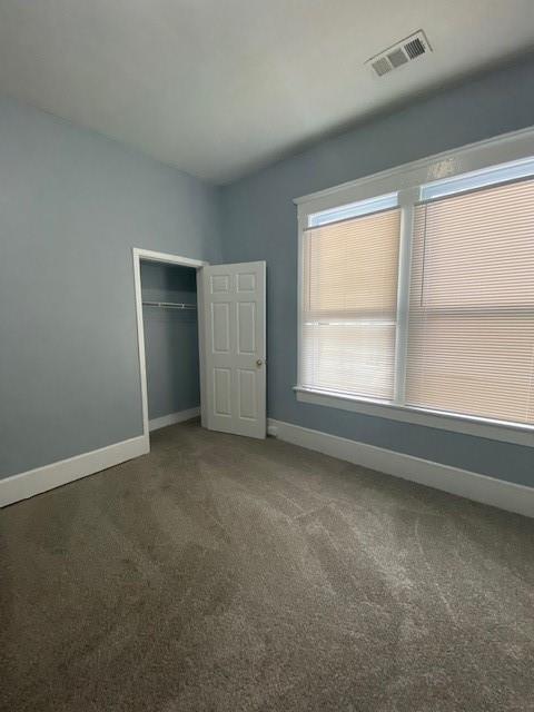 unfurnished bedroom with a closet and dark colored carpet