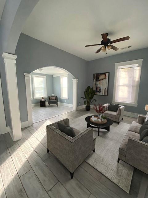 living room featuring decorative columns, ceiling fan, and light hardwood / wood-style floors