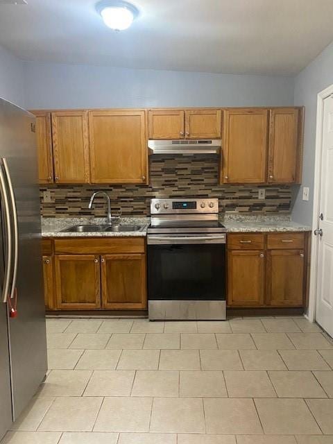 kitchen featuring light stone counters, sink, backsplash, and stainless steel appliances