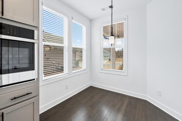 unfurnished dining area featuring visible vents, dark wood finished floors, and baseboards