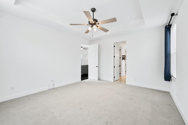 interior space with ceiling fan, light colored carpet, baseboards, a tray ceiling, and crown molding