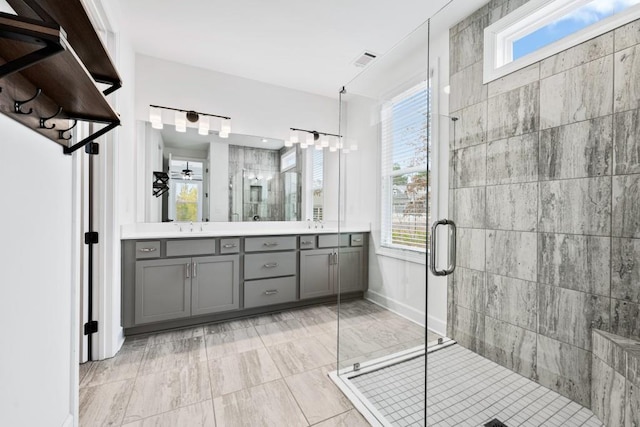 full bath featuring double vanity, a stall shower, plenty of natural light, visible vents, and a sink