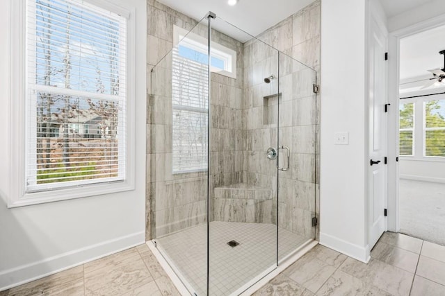 bathroom featuring ceiling fan, a shower stall, and baseboards