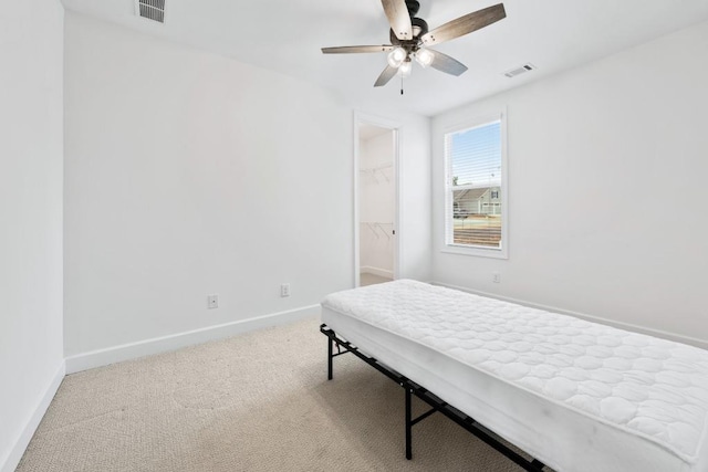 bedroom with a walk in closet, carpet flooring, visible vents, and baseboards