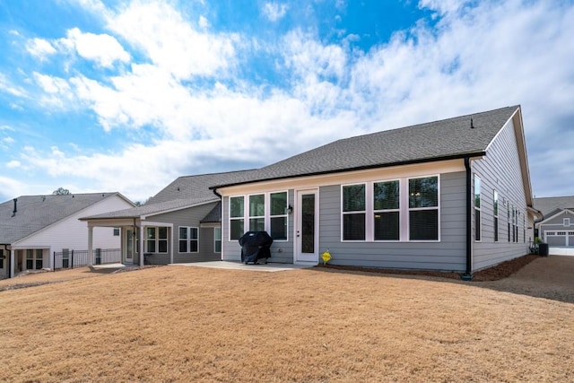 back of house featuring a patio, a shingled roof, and a lawn