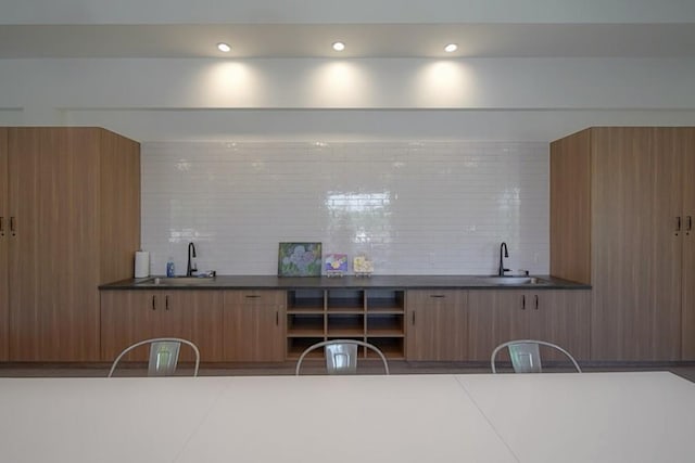 bar featuring indoor wet bar, backsplash, and a sink