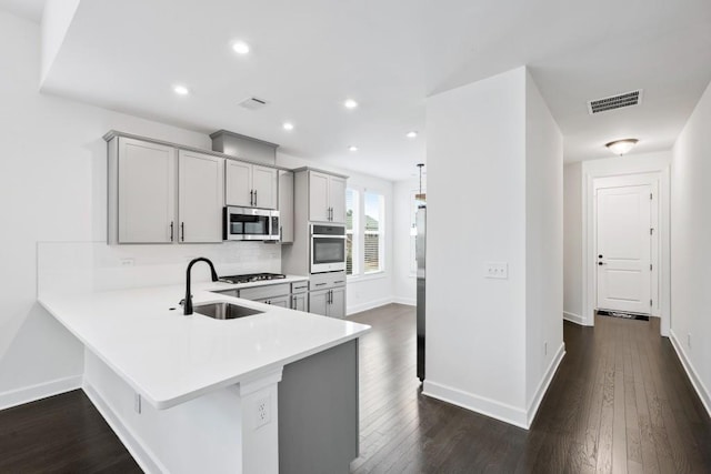 kitchen with stainless steel appliances, gray cabinets, light countertops, visible vents, and a sink