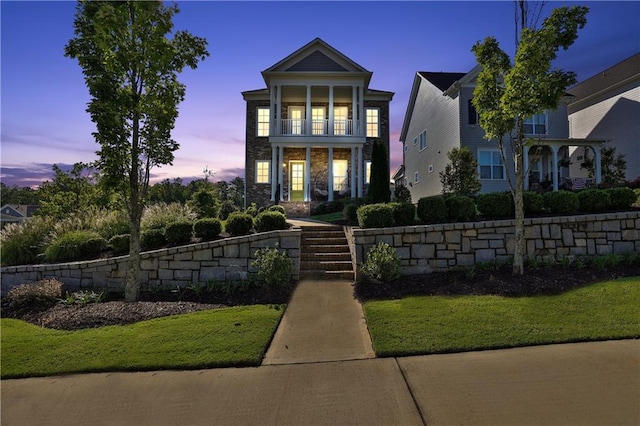 view of front of property featuring a balcony and a lawn