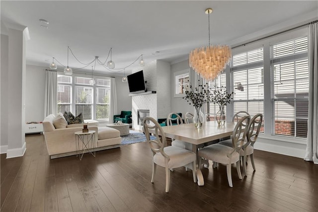 dining room with a fireplace, dark hardwood / wood-style floors, an inviting chandelier, and a wealth of natural light