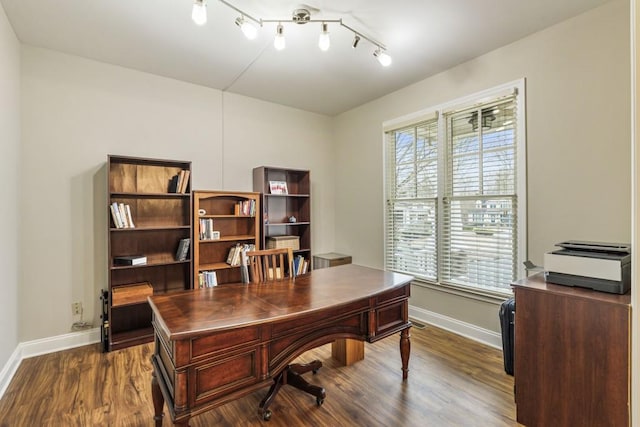 home office with track lighting, dark wood-style flooring, and baseboards