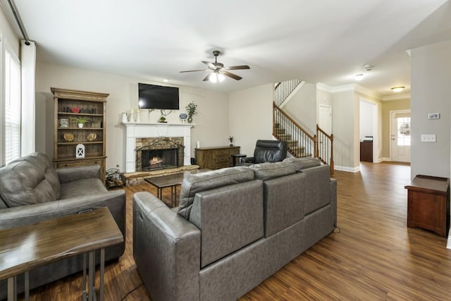 living room featuring baseboards, a ceiling fan, dark wood-style flooring, stairs, and a fireplace