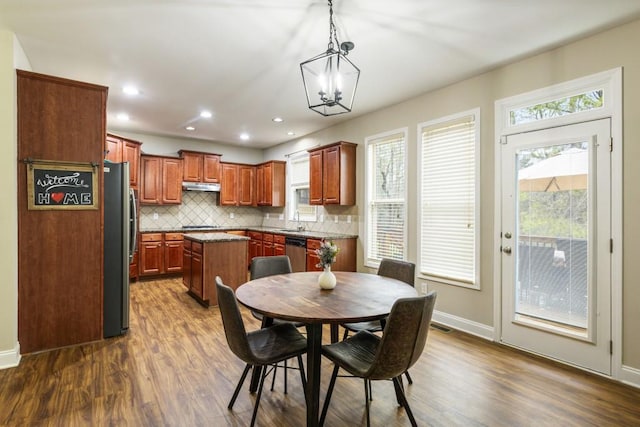 kitchen with tasteful backsplash, a kitchen island, appliances with stainless steel finishes, pendant lighting, and a sink