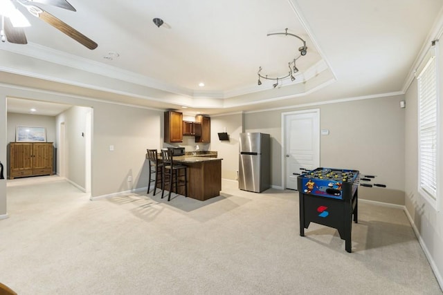 rec room featuring ornamental molding, a tray ceiling, light carpet, and baseboards