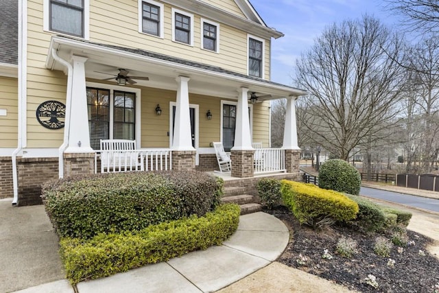 entrance to property featuring covered porch, brick siding, and ceiling fan