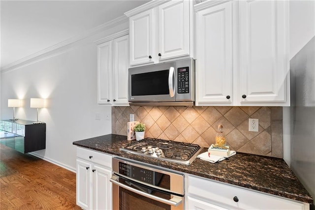 651 Coligny Ct, Atlanta, GA 30350 - kitchen with stainless steel appliances, light wood-style flooring, white cabinets, dark stone counters, and ornamental molding