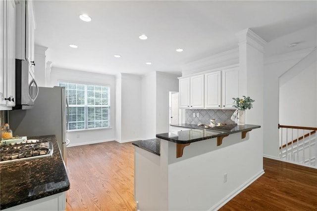 651 Coligny Ct, Atlanta, GA 30350 - kitchen featuring stainless steel appliances, a breakfast bar area, white cabinetry, dark stone countertops, and light wood-type flooring
