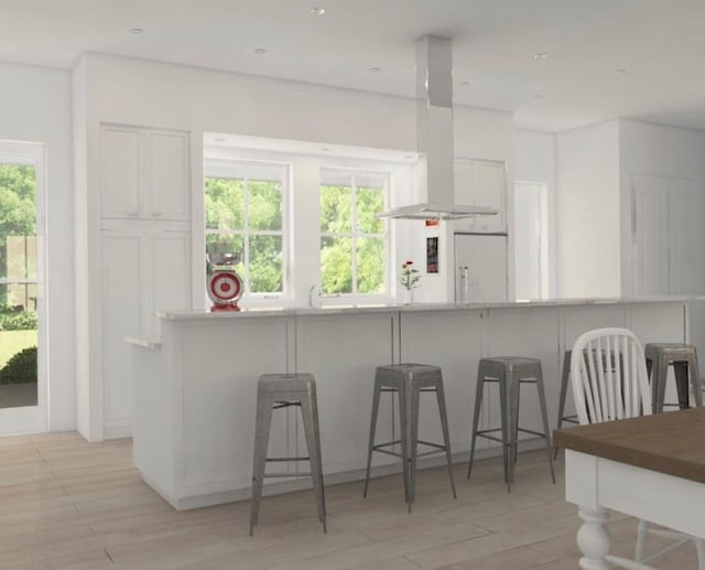 kitchen with plenty of natural light, a breakfast bar, white cabinets, and island exhaust hood