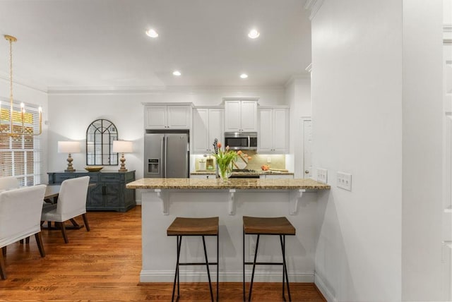 1227 Parkside Village Dr NW, Marietta, GA 30060 - kitchen featuring appliances with stainless steel finishes, a kitchen breakfast bar, ornamental molding, a peninsula, and a chandelier