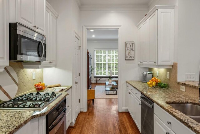 1227 Parkside Village Dr NW, Marietta, GA 30060 - kitchen with appliances with stainless steel finishes, crown molding, wood finished floors, white cabinets, and tasteful backsplash