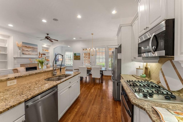 1227 Parkside Village Dr NW, Marietta, GA 30060 - kitchen with stainless steel appliances, a sink, ornamental molding, white cabinets, and a fireplace