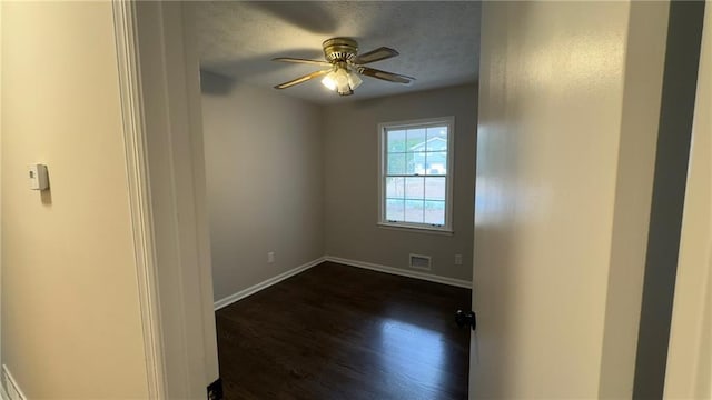 spare room with a textured ceiling, ceiling fan, and dark hardwood / wood-style floors