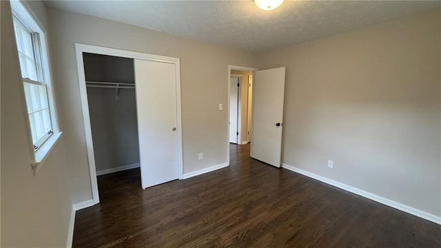 unfurnished bedroom with dark hardwood / wood-style flooring and a closet