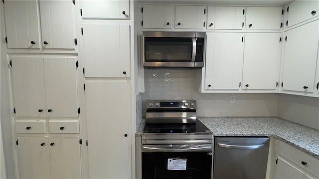 kitchen featuring white cabinets, decorative backsplash, light stone counters, and appliances with stainless steel finishes