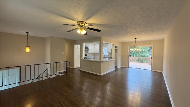 unfurnished living room with a textured ceiling, dark hardwood / wood-style flooring, and ceiling fan with notable chandelier