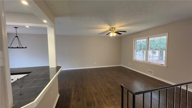 unfurnished room featuring ceiling fan with notable chandelier and dark hardwood / wood-style floors