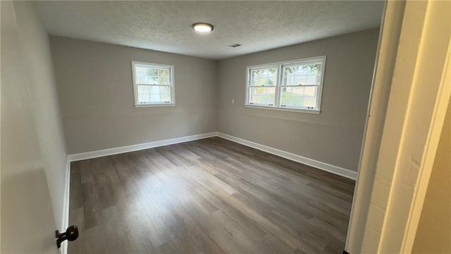 unfurnished room featuring a textured ceiling and dark hardwood / wood-style flooring