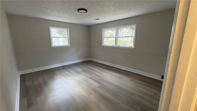 unfurnished room with a textured ceiling and dark wood-type flooring