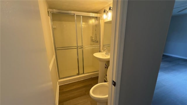 bathroom with ceiling fan, an enclosed shower, sink, and wood-type flooring