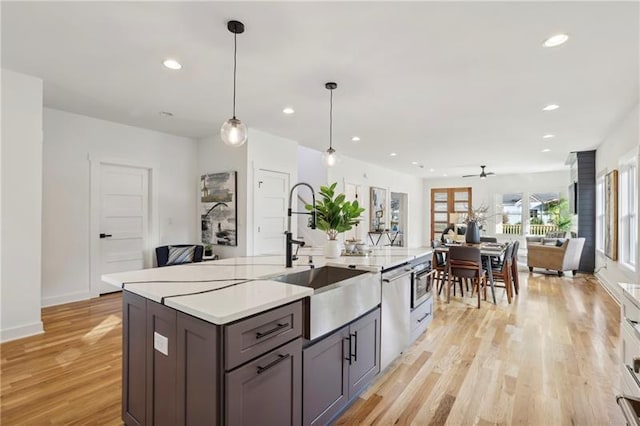 kitchen featuring pendant lighting, dishwasher, sink, ceiling fan, and light hardwood / wood-style flooring