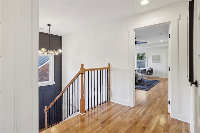 hall featuring wood-type flooring and a notable chandelier