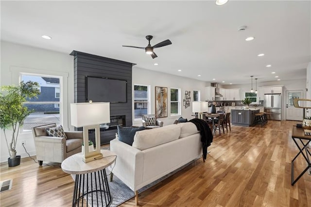 living room featuring a fireplace, light hardwood / wood-style floors, and ceiling fan