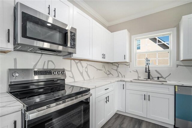 kitchen with sink, ornamental molding, appliances with stainless steel finishes, tasteful backsplash, and white cabinetry