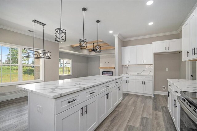 kitchen with decorative light fixtures, a kitchen island, white cabinetry, and light hardwood / wood-style flooring