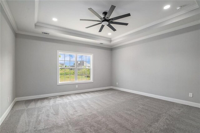 carpeted spare room with a tray ceiling, ceiling fan, and crown molding