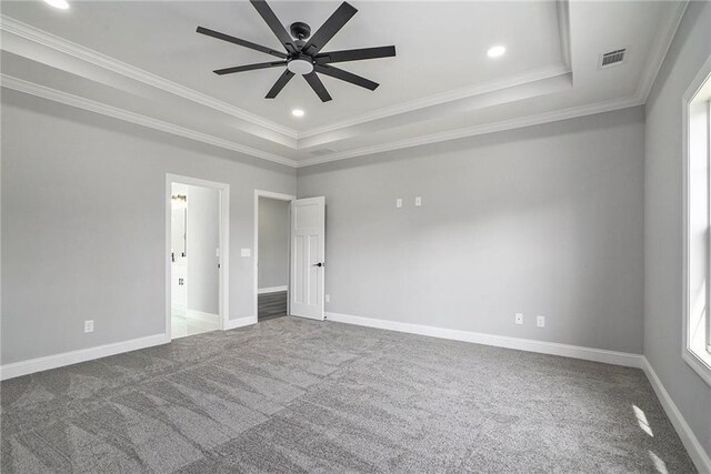 carpeted empty room featuring a tray ceiling, ceiling fan, and crown molding