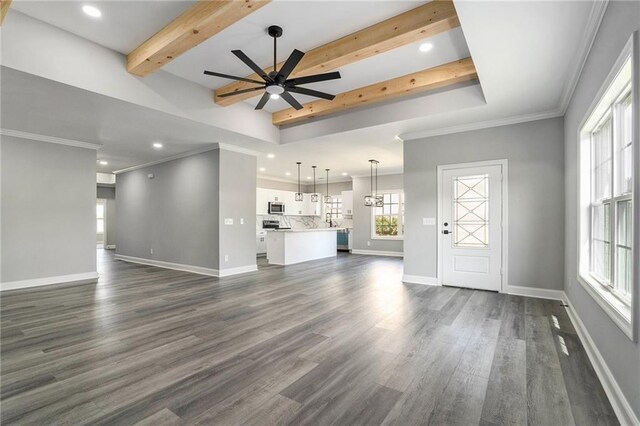 unfurnished living room featuring beam ceiling, dark hardwood / wood-style floors, ceiling fan, and ornamental molding