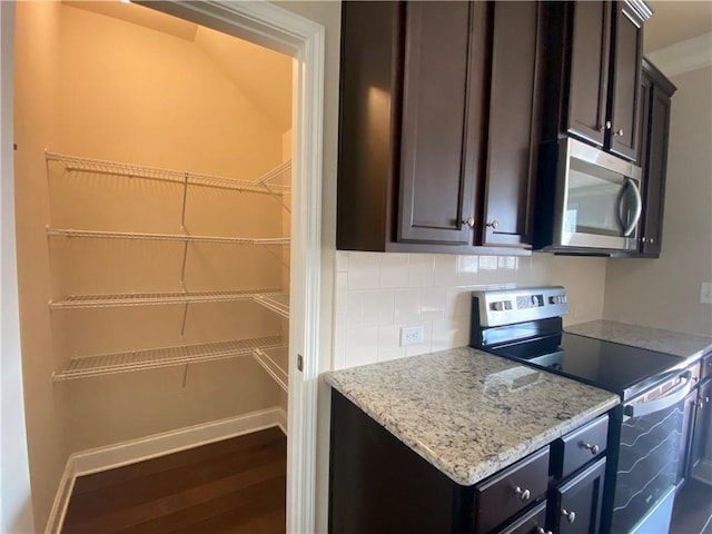 kitchen featuring appliances with stainless steel finishes, tasteful backsplash, light stone countertops, and dark brown cabinetry