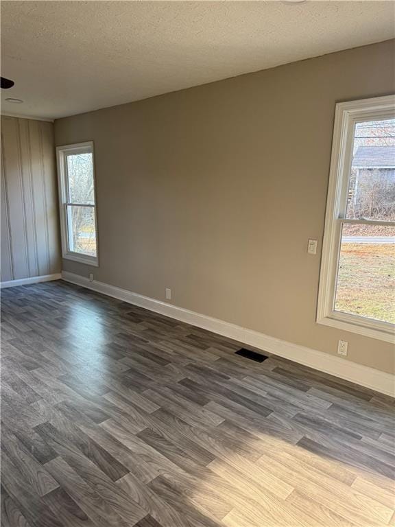 empty room with dark hardwood / wood-style floors and a textured ceiling